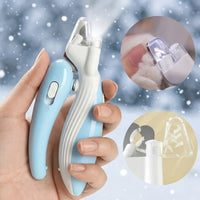 Pet nail trimmer held in a hand with a snowy background
